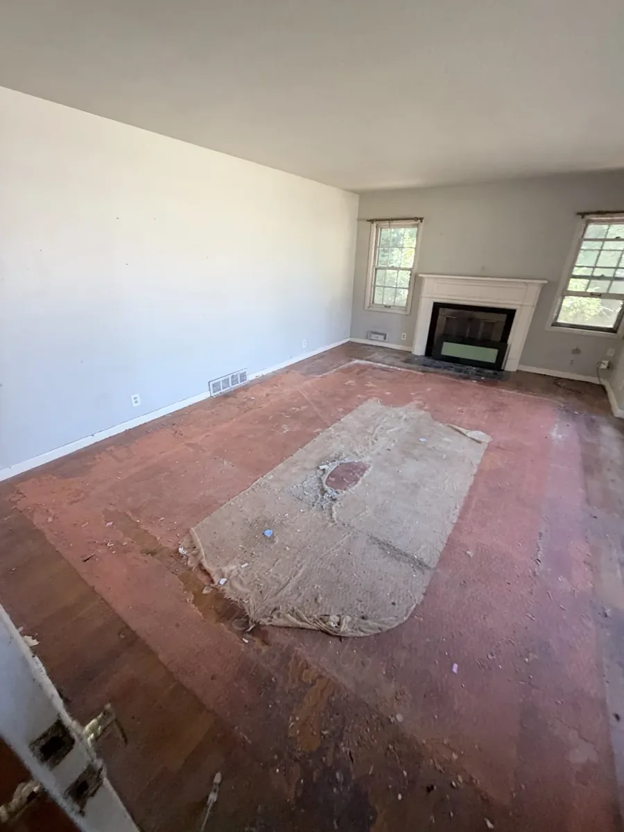 Same room after removal with exposed flooring and some carpet padding remaining